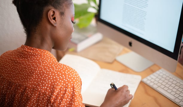 a woman sitting at a desk with a notebook and pen
