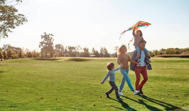 Familia tradicional con dos hijos caminando felices por el campo de golf de Bosque Real