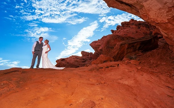 a bride and groom standing on a rock formation