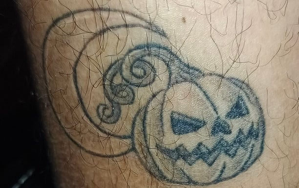 a tattoo on a man's leg with a pumpkin