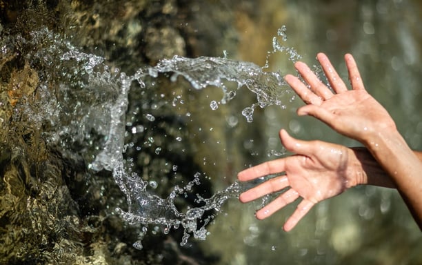 a person's hands are outstretched out of focus as they are touching the water