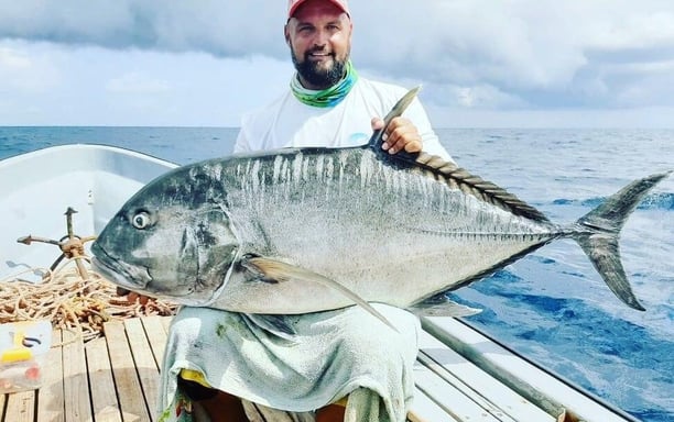 Angler holding a massive Giant Trevally on a Zanzibar fishing charter, perfect for deep-sea fishing 