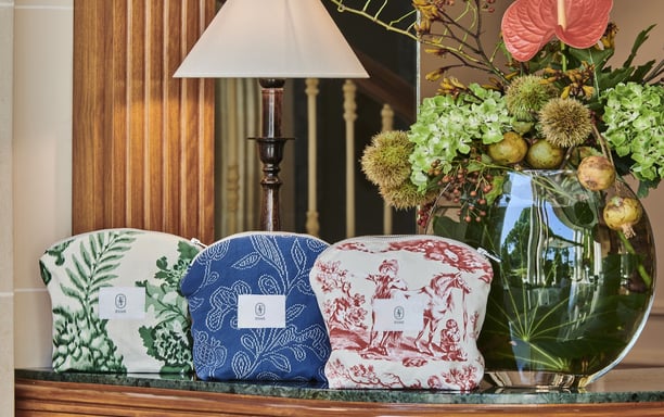 Pochettes ÉTOFÉ en tissu upcyclé, exposées dans un décor d’hôtel raffiné, motifs feuillage, broderie