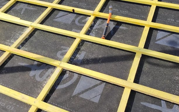 Installation de liteaux en bois sur un écran de sous-toiture lors de la rénovation d’une couverture à Audincourt, pour une me