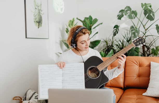 Online guitar lesson displayed on a computer screen with a virtual instructor