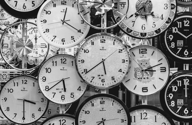 a bunch of clocks on a wall with many different clocks