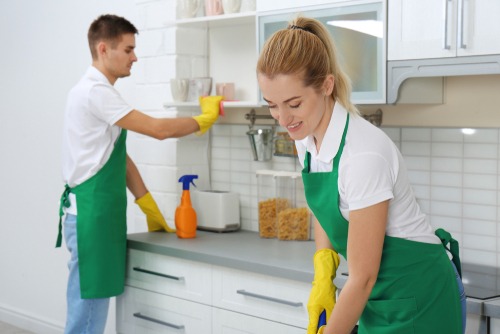 a man and woman cleaning a kitchen counter