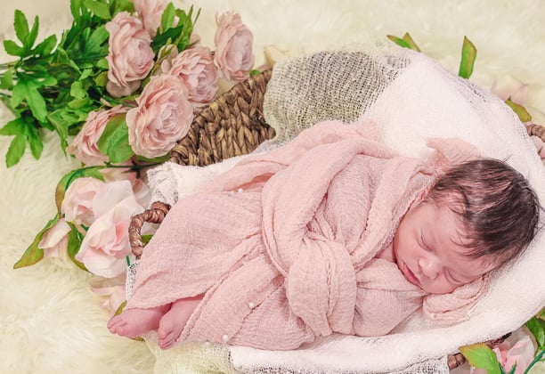 a newborn baby in a basket with flowers