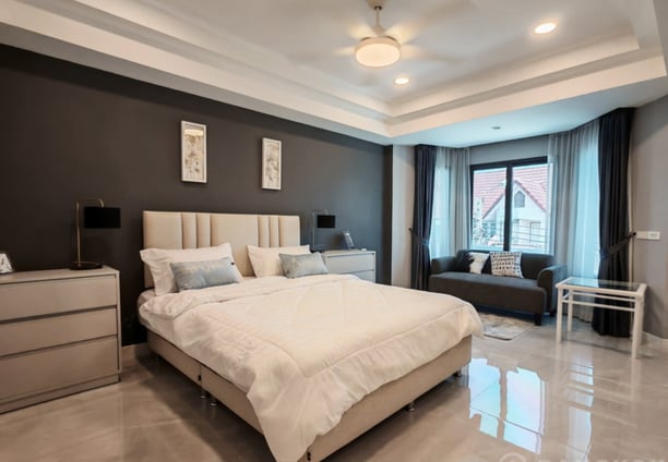 Primary bedroom with a bed and a couch. Thai Home for sale.