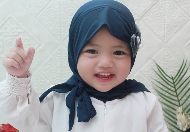 a baby wearing a blue scarf and a white shirt