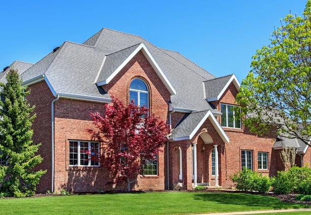 A stately brick house with lush landscaping 