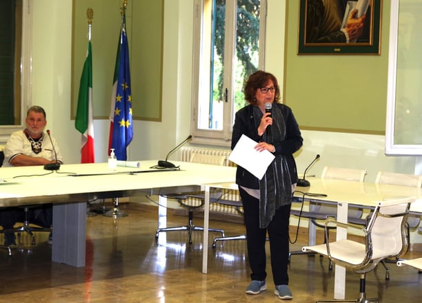 a woman standing in front of a table with a microphone