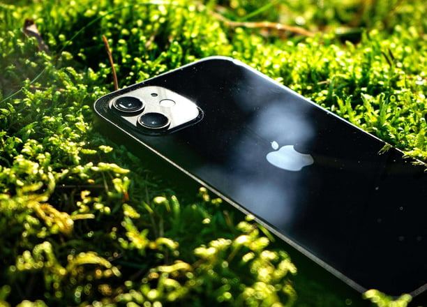 iPhone Km0 negro sobre musgo verde, destacando la sostenibilidad y la integración de la tecnología con la naturaleza.