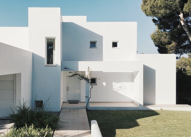a white house with a white wall and a tree