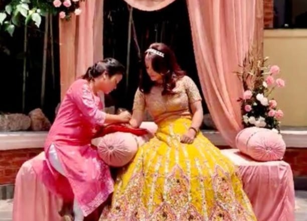 Henna artist doing henna on groom"s hand during mehendi ceremony