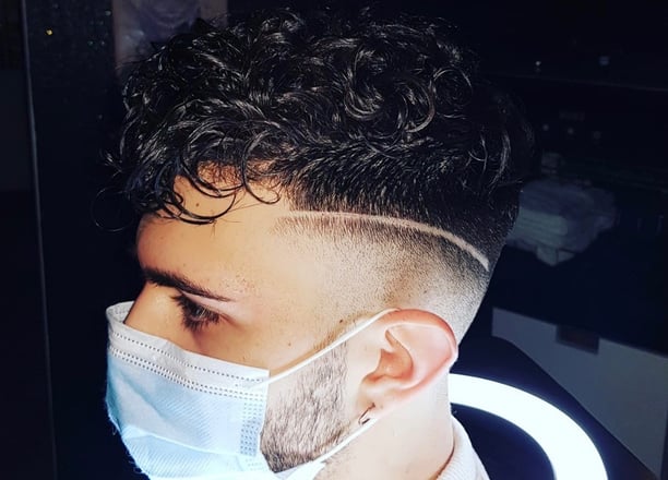 Taglio sfumato con riga incisa e capelli ricci.