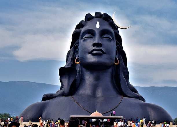 Lord Shiva statue with people gathering for darshan and pooja