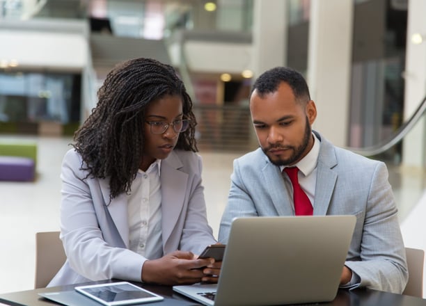 Two business professionals reviewing information on a laptop, representing administrative and legal support for enterprises.