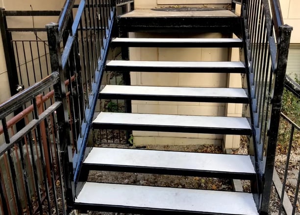 A sturdy metal staircase with concrete steps, built for durability and style. The strong steel frame