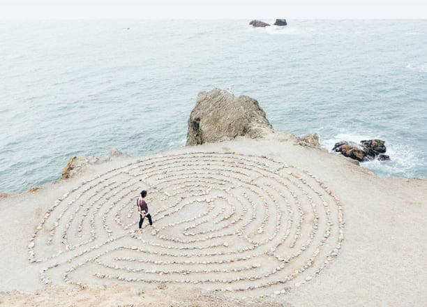 Une personne marche sur un labyrinthe façonné sur une plage