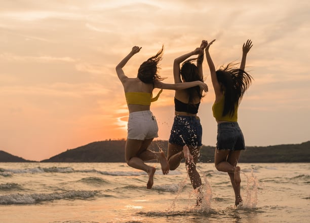 three women jumping in the air in the ocean
