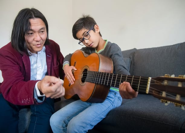 Guitar instructor demonstrating a playing technique to a student