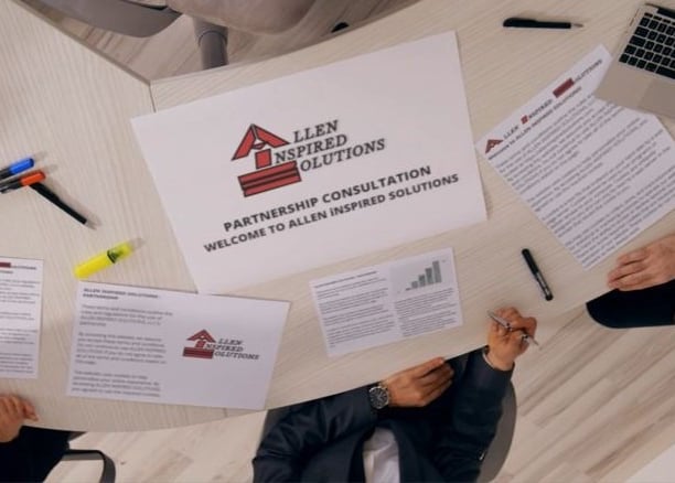 a group of people sitting around a table with AiS partnership papers