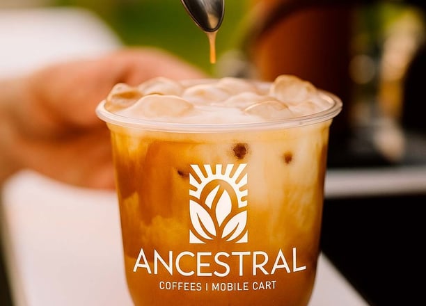 Guest enjoying a latte from a custom-branded coffee cart at a corporate event