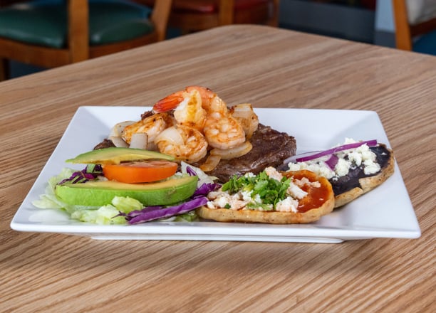 Surf and turf plate with shrimp, grilled steak, sopes and fresh salad served at Kraken Mar y Tierra