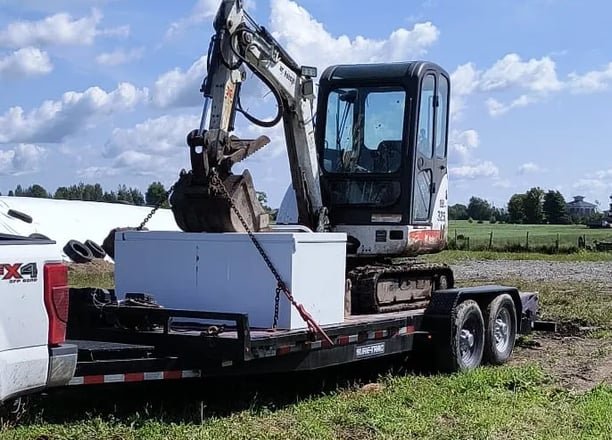 A flatbed trailer hauling a mini excavator 