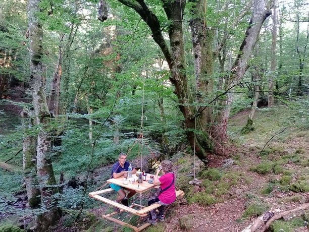 Hanging table in the forest with people having breakfast
