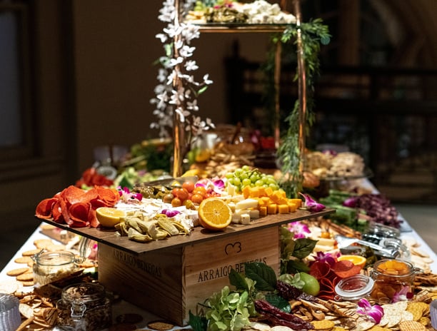 Large charcuterie display with fresh fruit, meats, cheese, crackers displaye on a large glass tiered