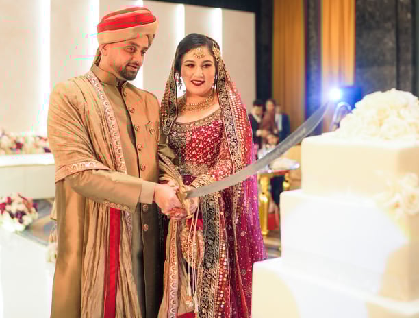 a man and woman are cutting into a wedding cake