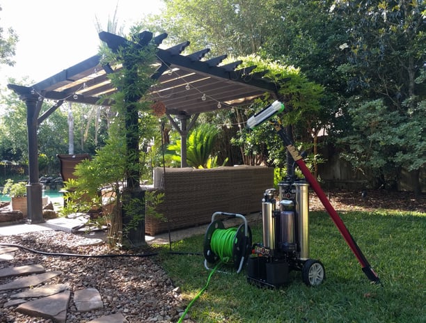 Window cleaning equipment and water filtration system setup in a backyard next to a gazebo and pool