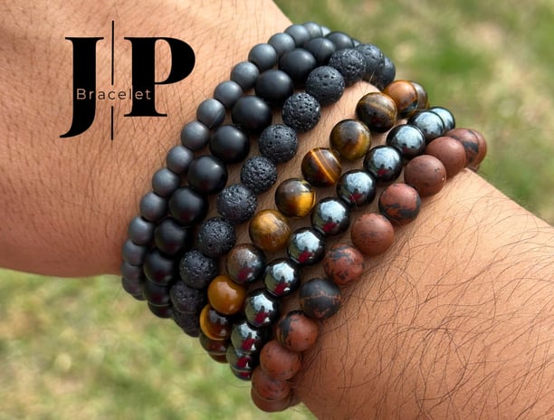 Muñeca masculina con varias pulseras artesanales de piedras naturales en tonos negros, marrones