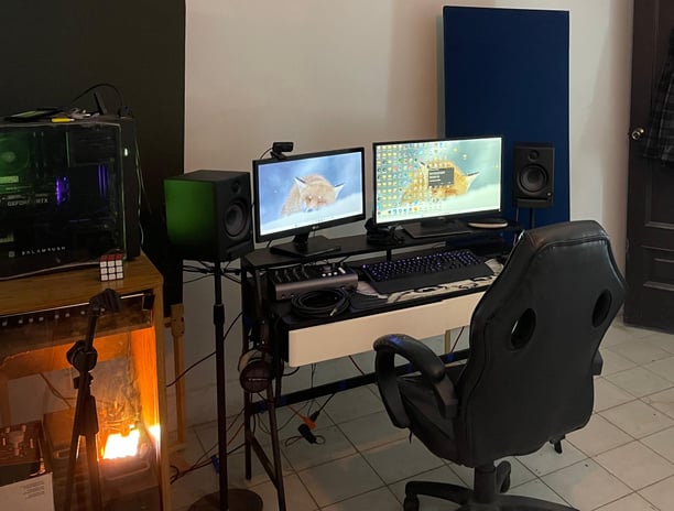 a man sitting at a desk with two monitors and a laptop