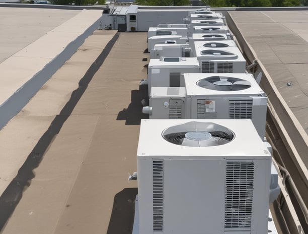 Numerous air conditioning units are densely packed on the exterior wall of a multi-story building. The image shows a very urban setting, with a grid-like arrangement of metal platforms supporting the units. Adjacent to this setup is a zigzagging metal staircase, leading to various floors of the building. The overall appearance is industrial and cluttered.