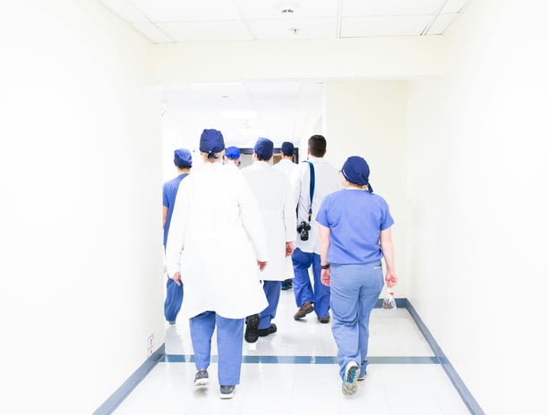 group of doctors and nurses in scrubs walking down a hospital corridor to their OET exam.