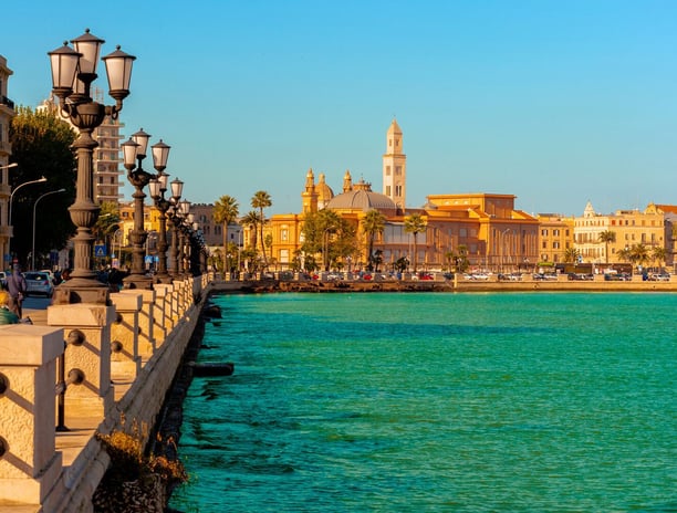 a Bari city street with a bridge and a boat in the water