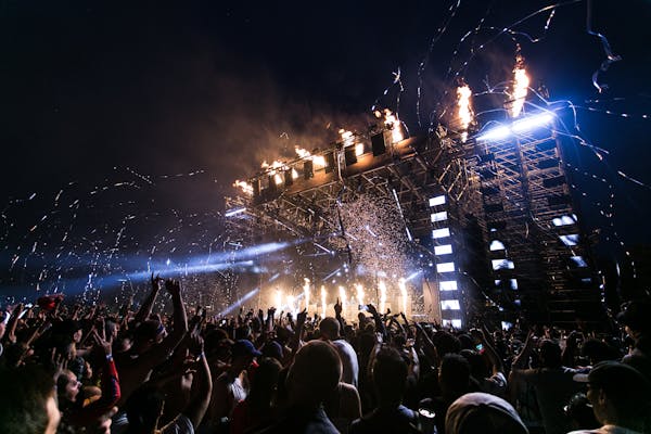 a crowd of people standing around a stage with fireworks