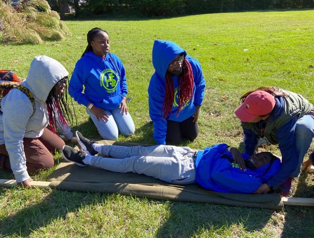 Youth learning to make a stretcher with a blanket and sticks