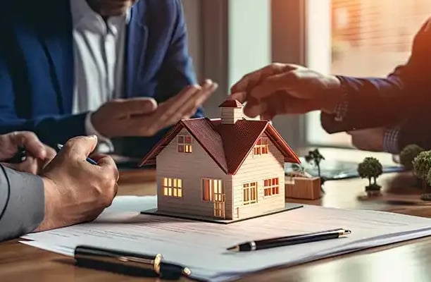 Real estate professionals discussing property maintenance and management with a miniature house mode