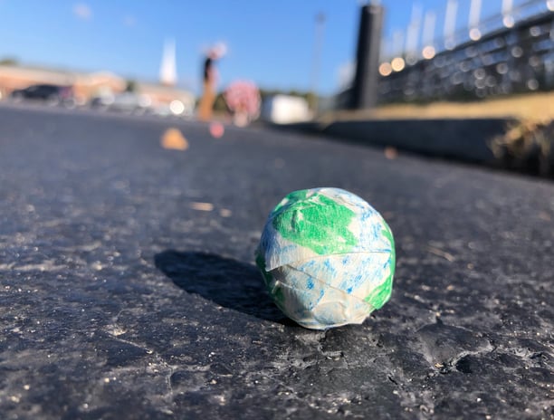 a model of the earth sitting on the ground with students and school in the background