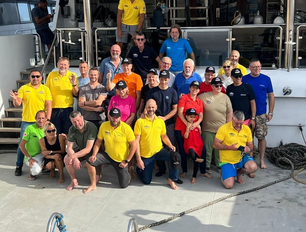 a group of people standing on a diving safari boat