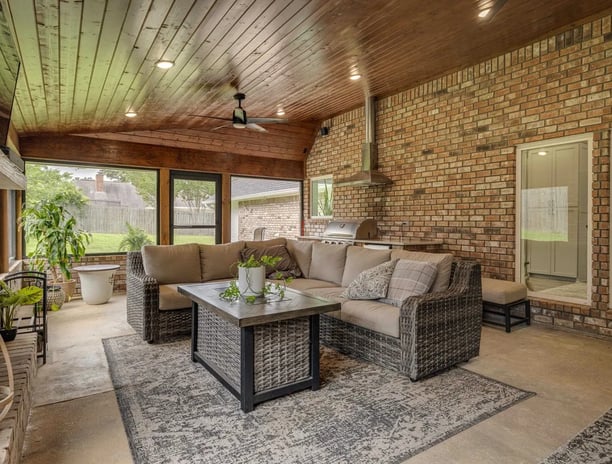 A photo of a screened porch with outdoor kitchen and living area