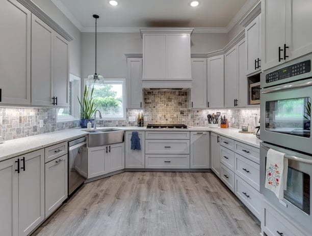 A photo of a remodeled kitchen with light cabinets and wooden floors.