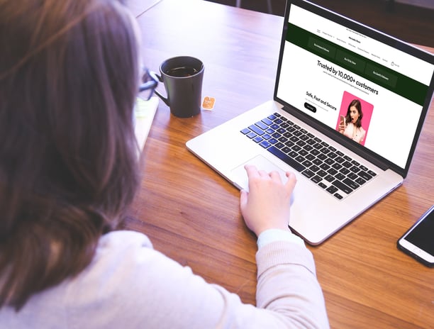 a woman sitting at a table with a cup of coffee and a cell phone, visiting mariadia.store website