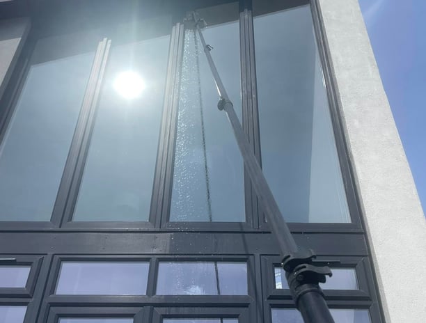 outdoor cleaning services Fife - extendable brush cleaning a window reflecting the sun