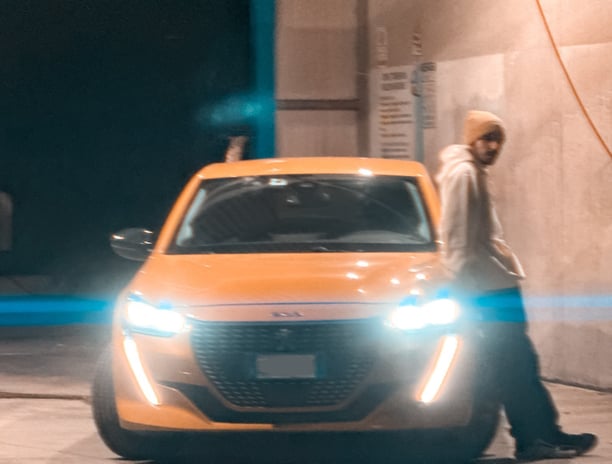 Ragazzo accanto a Peugeot 208 accesa. Passione per le auto raccontata in un blog autentico