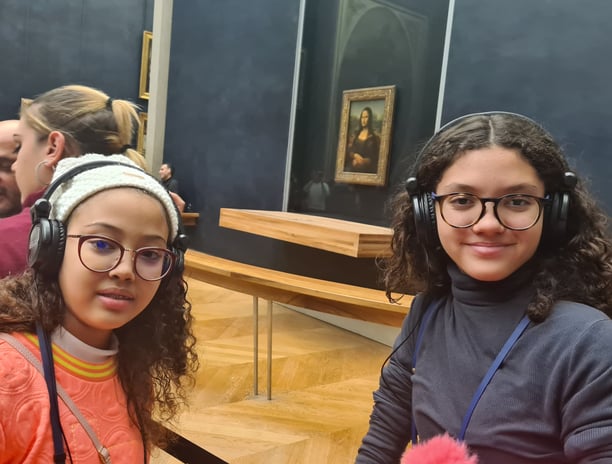 Duas adolescentes com autoguia em frente a obra de arte Monalisa no museu Louvre em Paris